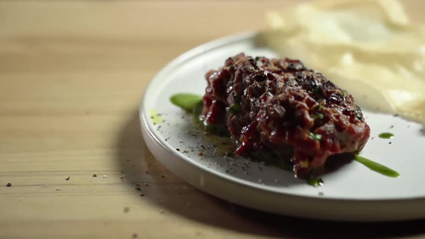 Seasoning being poured onto a tuna tartare on a plate