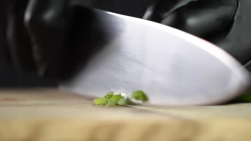 Vegetables being chopped with a knife on a wooden cutting board