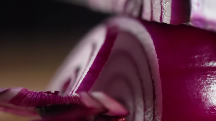 Close up of a red onion being sliced with a chef knife