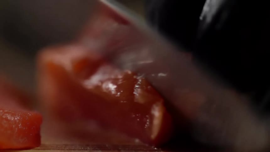 Cook with black gloves cuts salmon for sushi on a cutting board