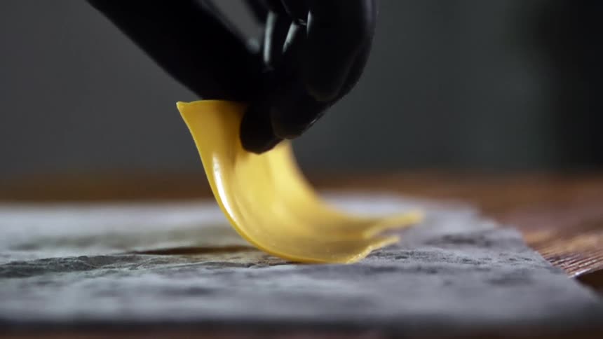 A gloved hand lays a slice of cheddar cheese on a plate