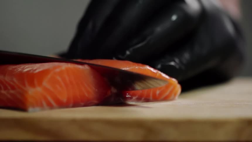 A chef cuts into a salmon fillet on a bias