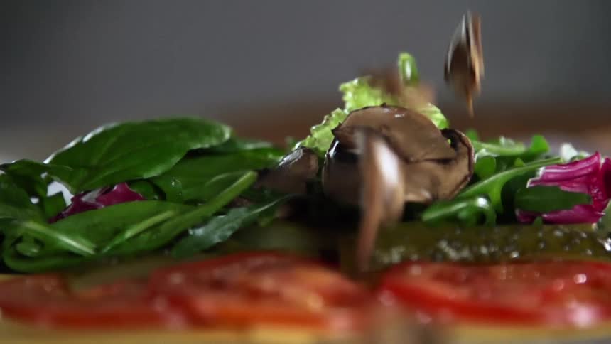 Mushrooms being dropped on top of vegetables
