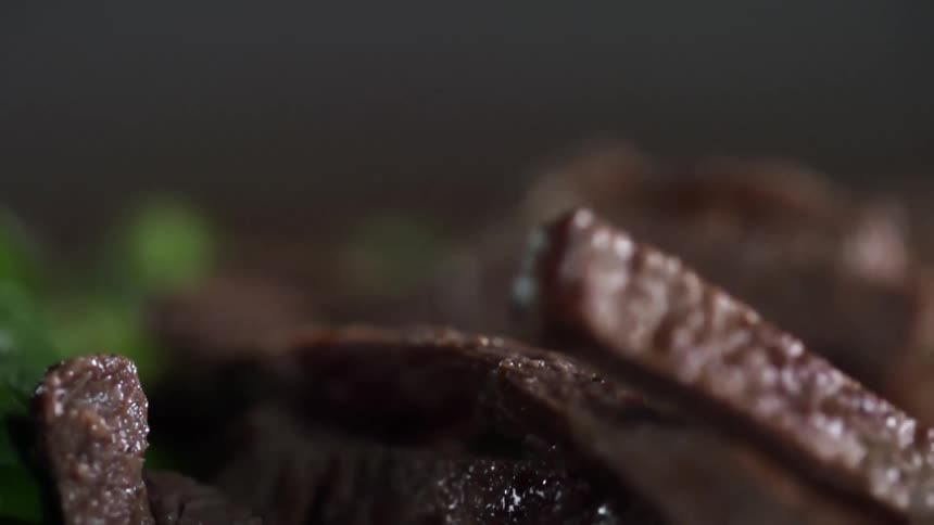 Meat falling on to a plate of greens