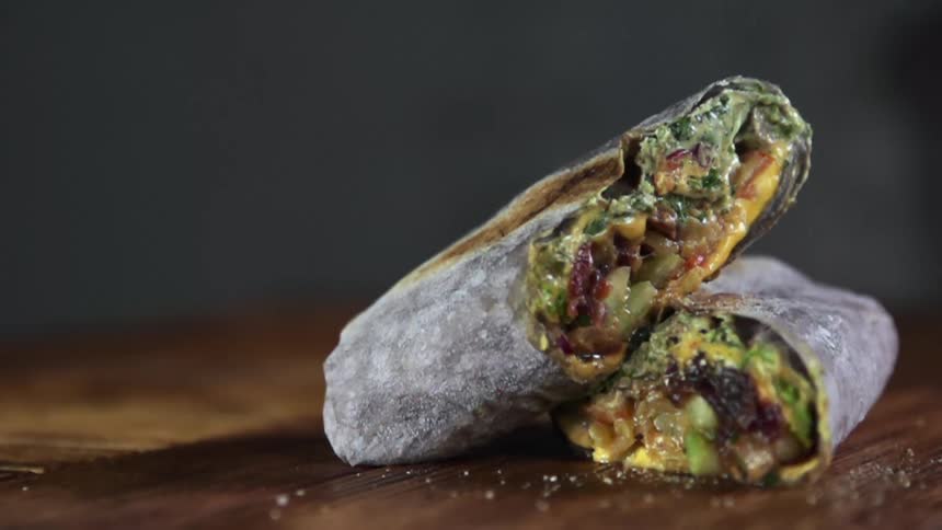 Grains of salt fall on halves of a burrito stacked atop one another