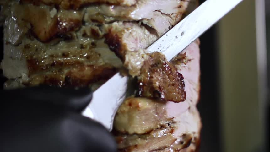 A person slices pieces of meat off a large chunk