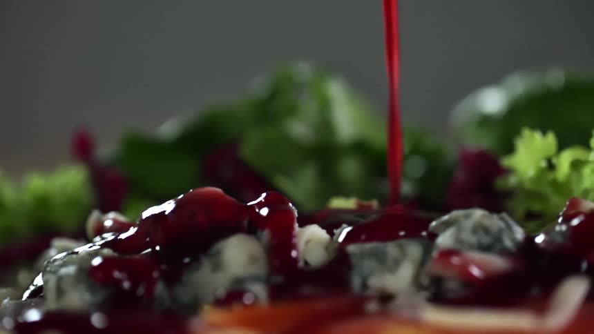 Sauce being poured onto food with vegetables in the background