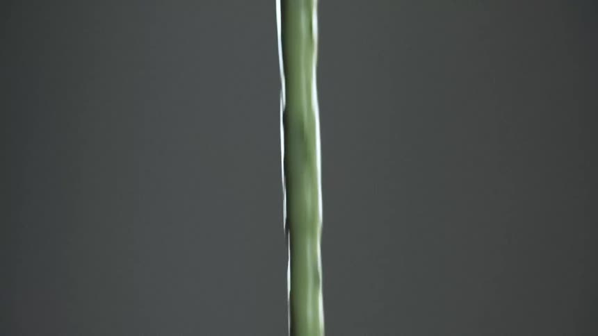 A green liquid being poured with a gray background