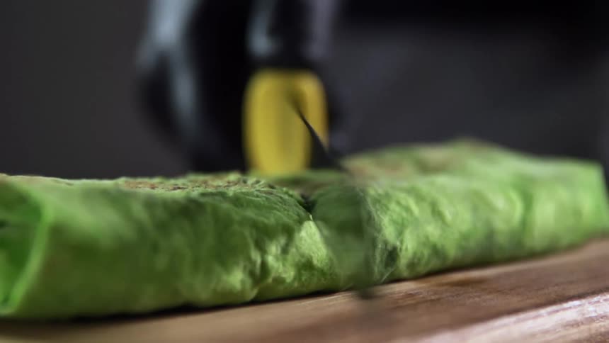 A person cuts the wrap in half with a knife