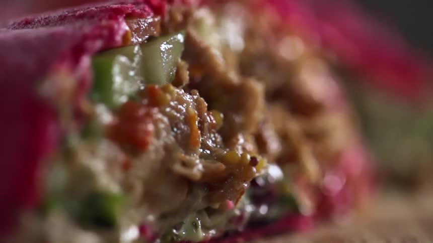 The burrito with a red tortilla sliced open to reveal the contents