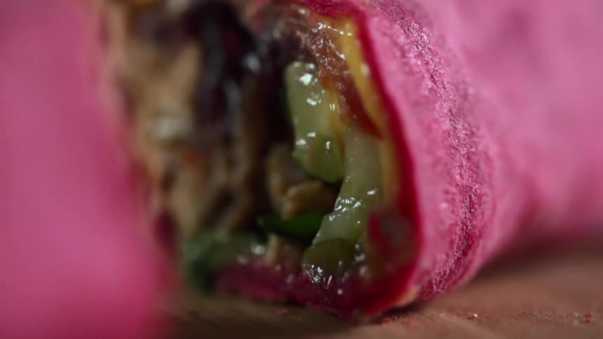 A sliced wrap sandwich is pulled apart exposing the glistening cooked filling