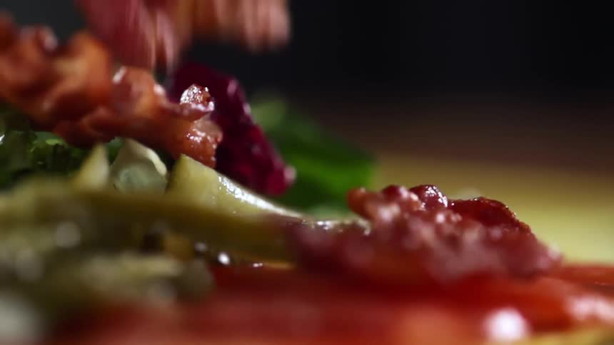 Small bacon bits fall over salad in a plate