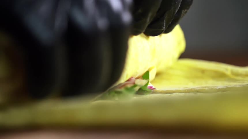 A person is rolling up some food in a wrap