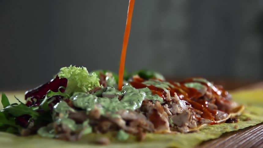 Sauce is being poured on the food in the tortilla
