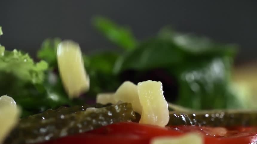 Chopped onions falling on pickles and tomatoes
