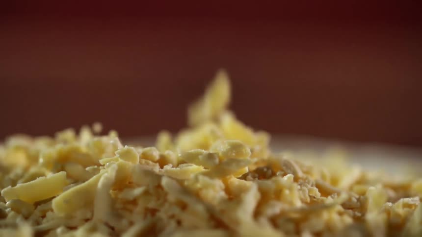 Cheese falling on to a pizza crust