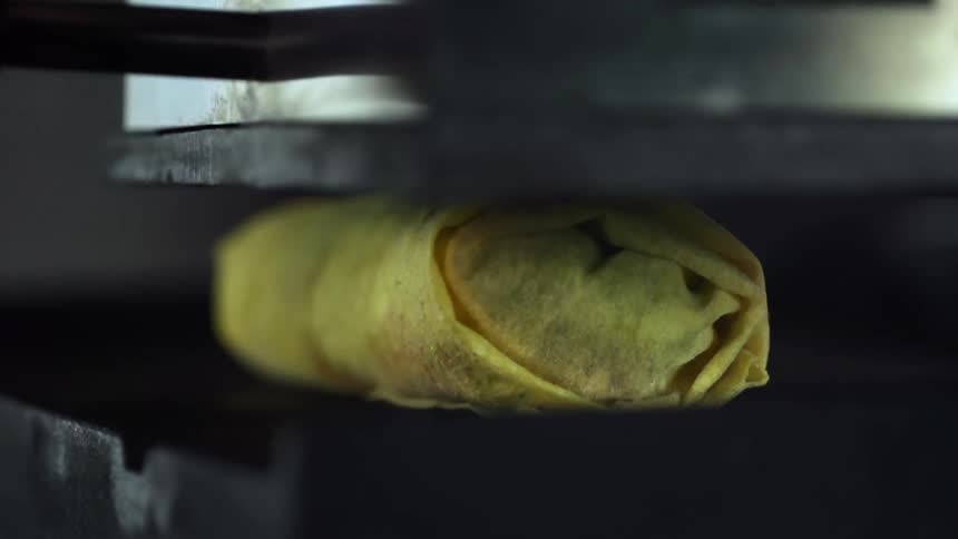 A burritos cooks between a metal press