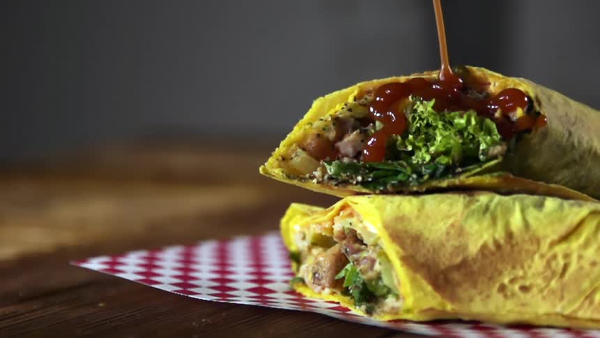 Sauce is poured on the burrito