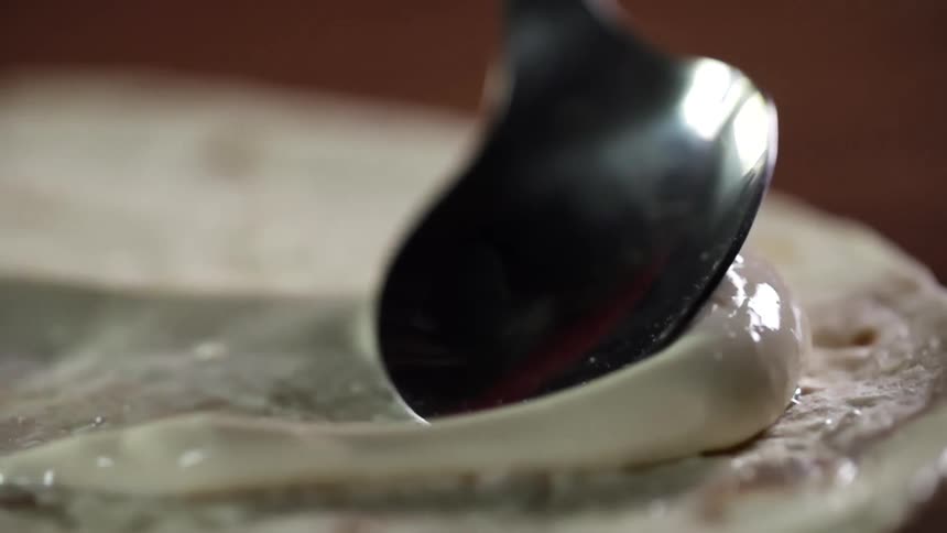 Sauce being spread on dough