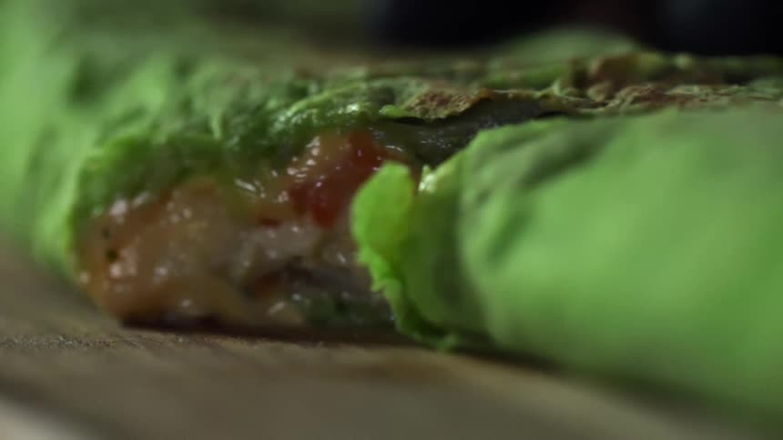 Cheese oozes from a spinach tortilla quesadilla thats been cut in half
