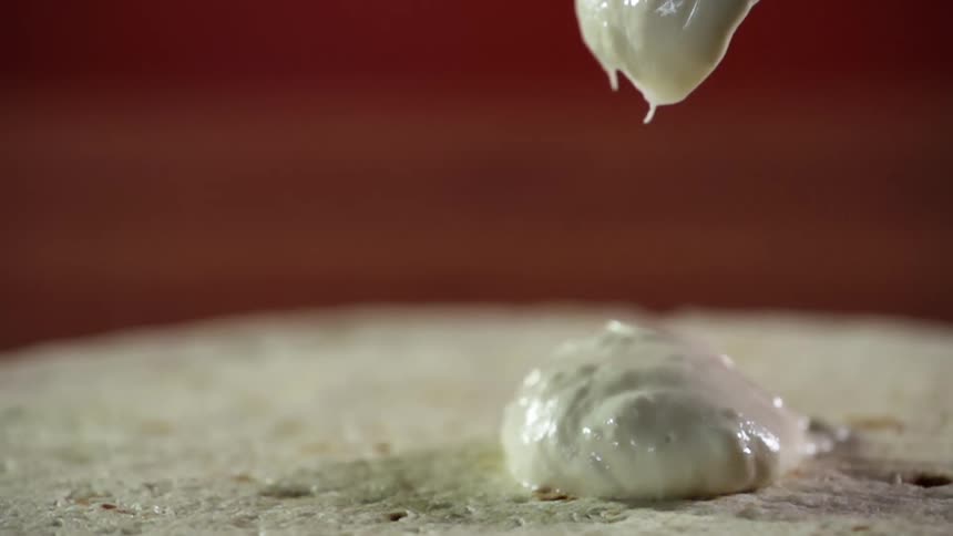 Sauce being put on pizza dough