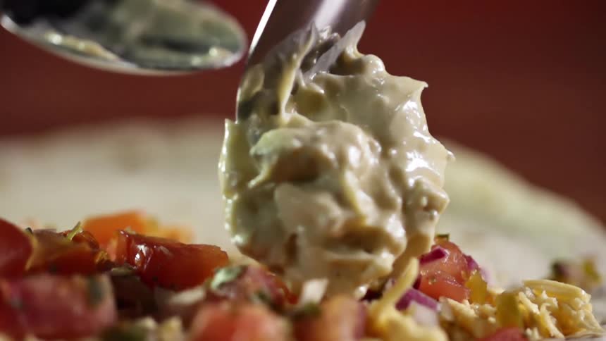 A creamy piece of food is dropped on top of a meal