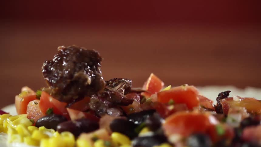 Chopped cooked beef falling atop of vegetables in a flour tortilla