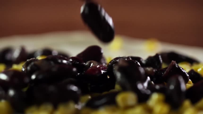 Black beans are added to a plate of corn