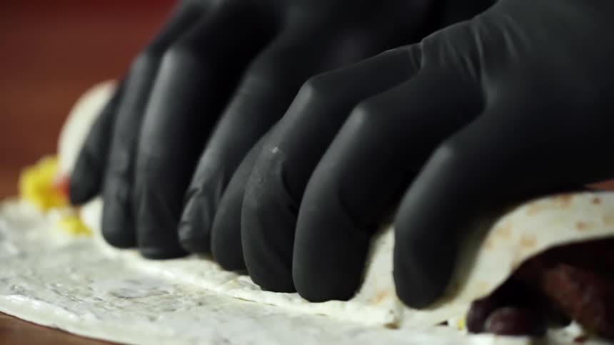 A person rolls ingredients in to a tortilla