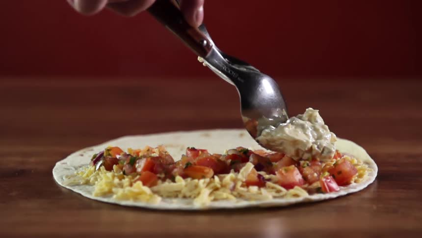 A person uses a spoon to put chicken salad on a plate