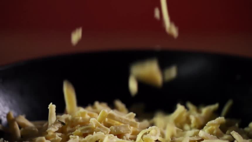 Shredded cheese is dropped into a black bowl