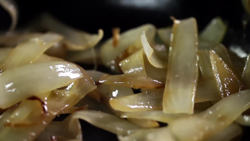 Sliced onions are being dropped and roasted in a skillet