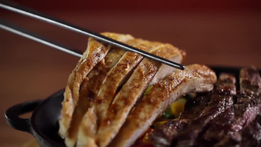 Serving pork belly strips with chopsticks on a iron cast pan
