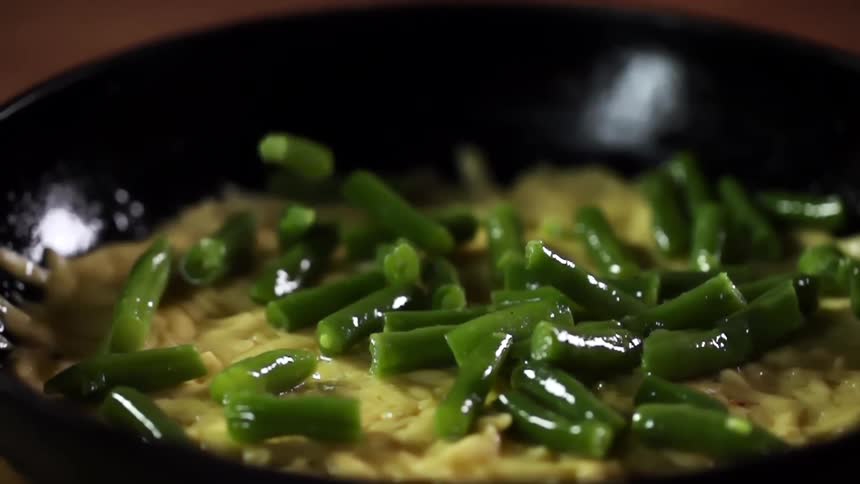 Green beans falling into a bowl of noodles