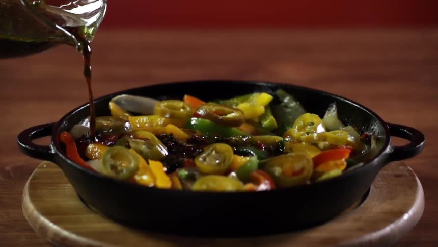 Teriyaki sauce is poured into a pan of sauteed vegetables