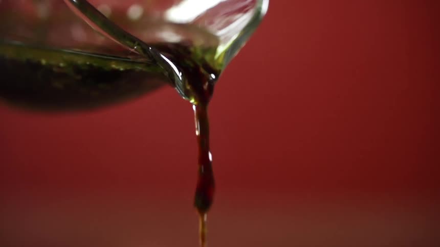 Pan drippings and sauce are poured out of a glass measuring cup with spout