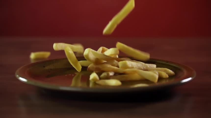 Fries fall onto brown plate place on flat surface