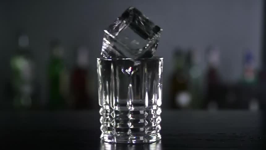 Large ice cube rotates on the rim of a glass