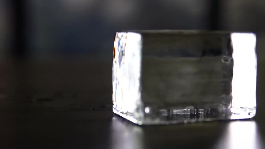 An ice cube slowly spins atop a table