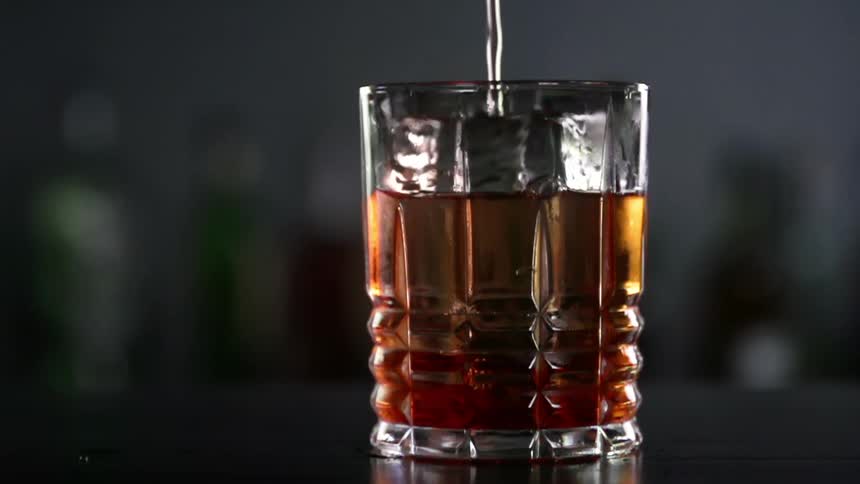 Close up of amber alcoholic beverage liquid pouring into a glass