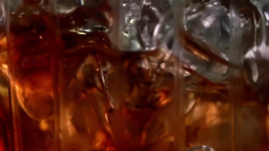 Ice cubes move around in a glass of alcoholic beverage
