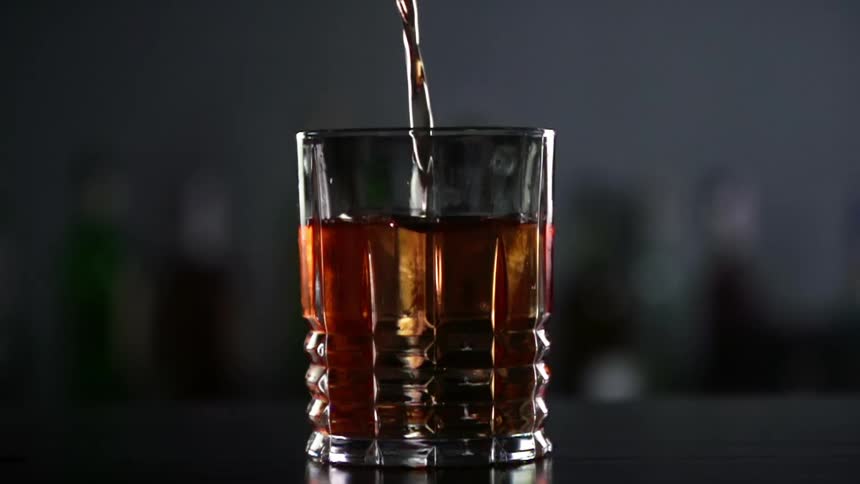 Alcohol is being poured into the small glass