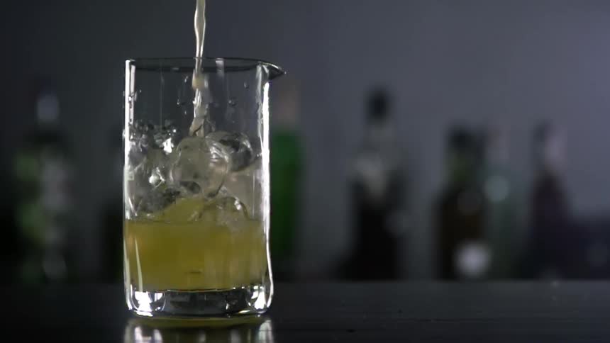 An alcoholic beverage being poured in to a glass on a bar top