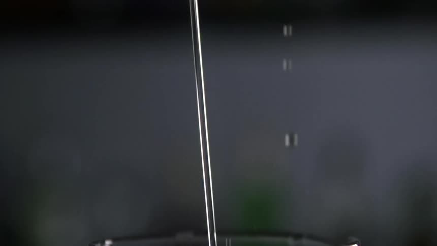 A drink is being poured into a glass on a dark background
