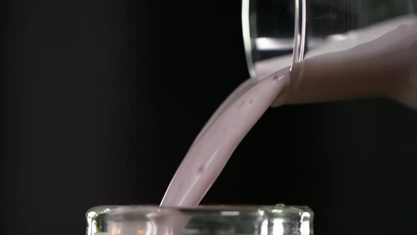 A berry falls as a cocktail is being poured in to a glass