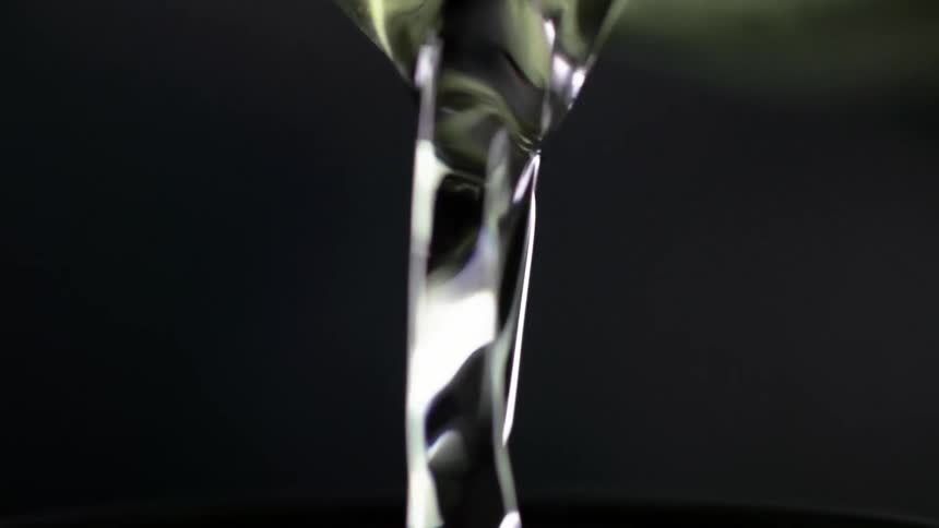 White wine pours from a glass jar