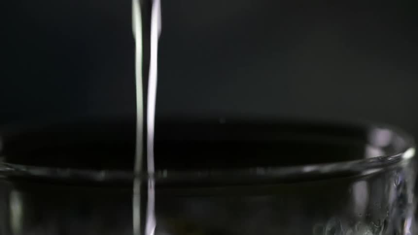 A glass is being filled wih an alcoholic beverage