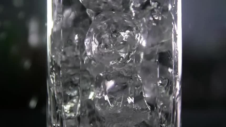 Ice cubes are being dropped into a glass
