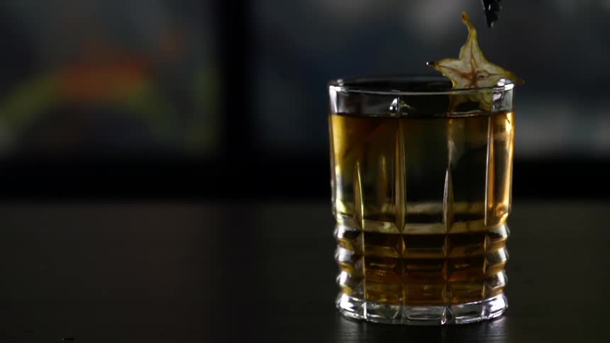Star fruit being set on the edge of a glass of cocktail