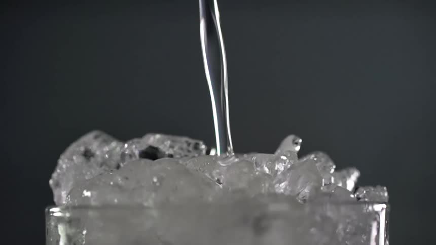 Cocktail being poured into a glass filled with crushed ice